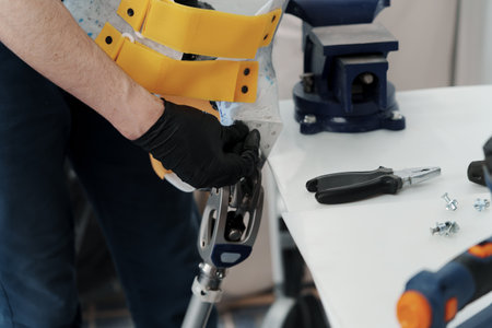Male master in gloves fixing hip disarticulation prosthesis using screwdriverの写真素材