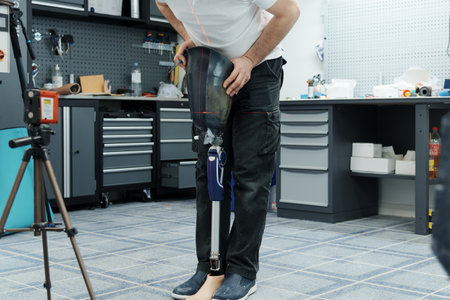Crop unrecognizable craftsman adjusting and bending modern prosthetic leg at knee sectionの写真素材