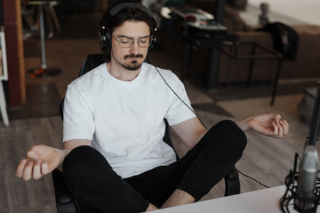 Young male musician meditating in recording studioの写真素材
