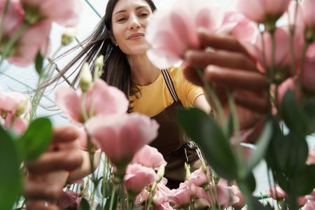 Pretty woman working with flowers in the green house
