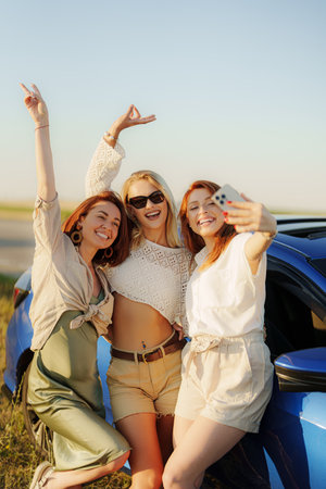 Cheerful women taking selfie while having fun by carの写真素材