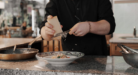 Crop male cook grating Parmesan cheese into dishの写真素材