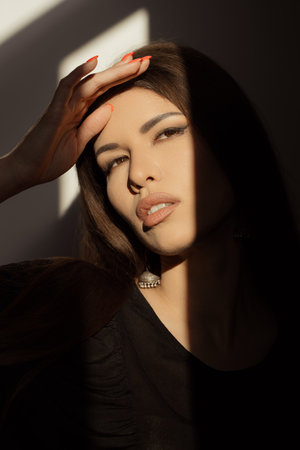 Elegant Woman Posing in Dramatic Sunlight and Shadow Contrast in Studio