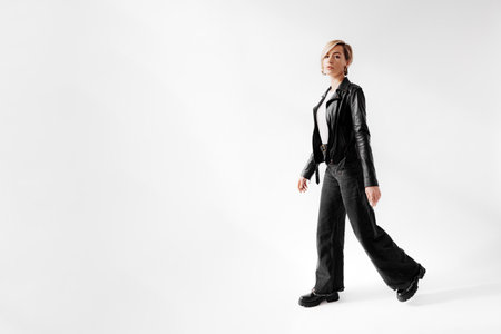 Chic Young Woman Striding in Leather and Denimの写真素材