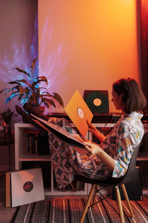 Young woman enjoying vinyl records in cozy home setupの写真素材