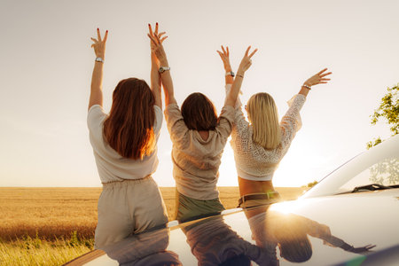Friends celebrating freedom on a road trip at sunsetの写真素材