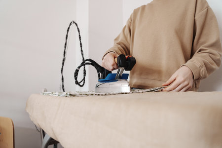 Craftswoman ironing fabric in home sewing workshopの写真素材