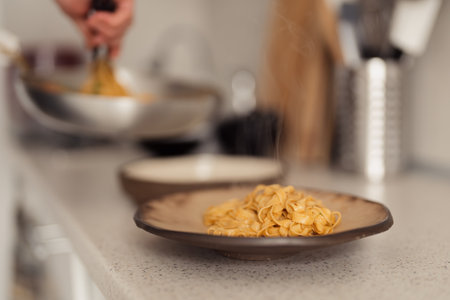Freshly cooked pasta dish in kitchen settingの写真素材
