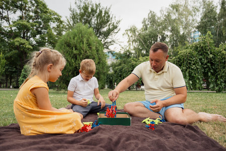 Father and children playing with toy building blocks outdoors