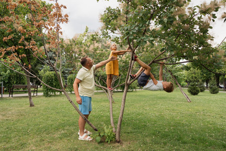 Father and children playing on a tree in the park