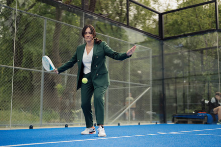 Woman in green suit playing padel tennis on outdoor courtの写真素材