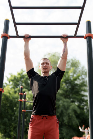 Determined man doing pull-ups at an outdoor fitness park