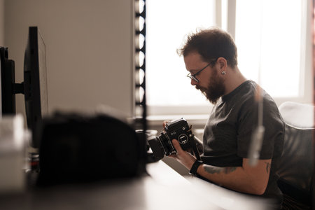 Photographer examining vintage camera indoorsの写真素材