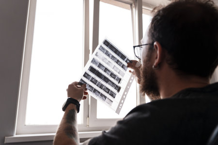 Photographer examining film negatives by the windowの写真素材