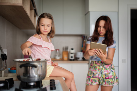 Mother and daughter cooking together in the kitchen with tabletの写真素材