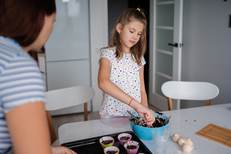 Young girl baking cupcakes in a modern kitchen settingの写真素材