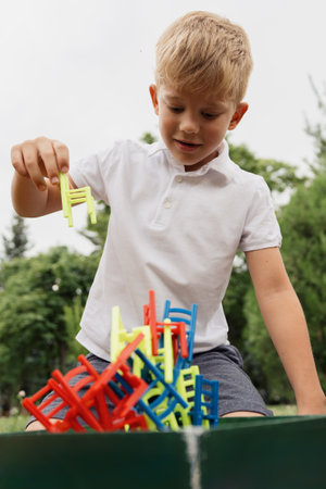 Young boy stacking colorful chairs in an outdoor park