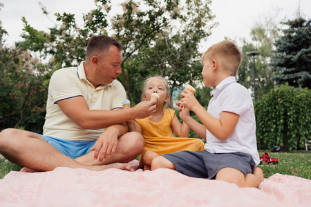 Family enjoying ice cream together on a picnic blanket outdoors