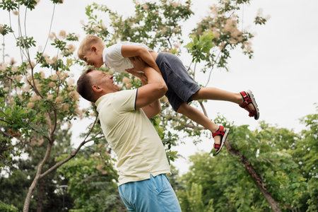 Father playing with son outdoors in park on summer dayの写真素材