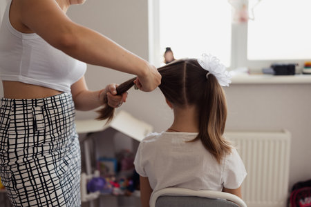 Mother Braiding Daughters Hair at Homeの写真素材