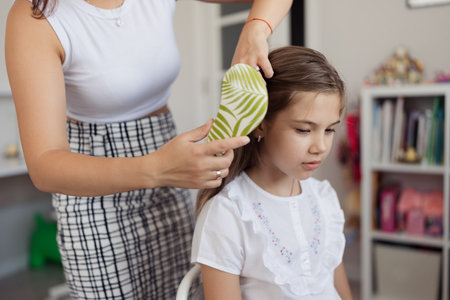 Mother Combing Daughters Hair at Homeの写真素材