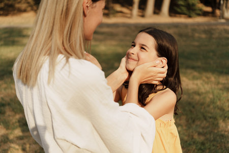 Mother and daughter sharing a loving moment outdoors in a parkの写真素材