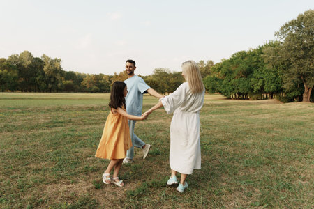 Happy family playing together in a sunny green park setting outdoorsの写真素材