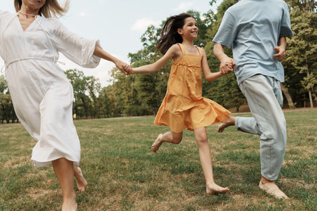 Happy family running together in a sunny park, enjoying outdoor funの写真素材