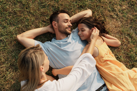 Happy family relaxing on grass enjoying a sunny day outdoors togetherの写真素材