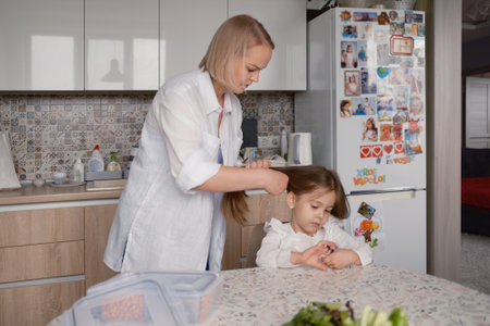 Mother helping daughter prepare for school in the kitchenの写真素材