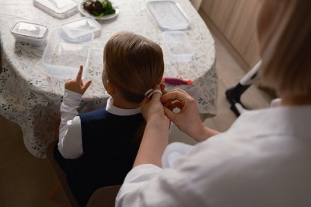 Mother preparing daughters hair for school in the morningの写真素材