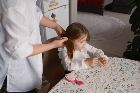 Mother styling her daughters hair before school in the morningの写真素材