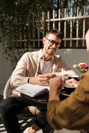 Smiling man having a conversation at an outdoor cafe tableの写真素材