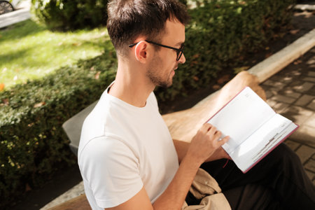 Young man enjoying a peaceful moment with a book outdoorsの写真素材