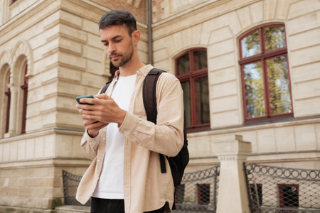 Young man using smartphone outdoors near historic buildingの写真素材