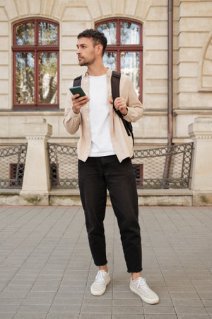 Confident young man exploring city with smartphone in handの写真素材