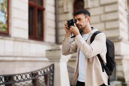 Young man taking photos with camera outdoors in cityの写真素材