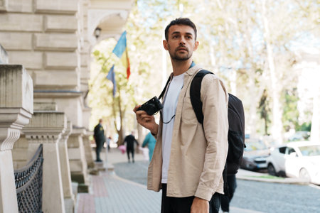 Young traveler exploring city streets with backpack and cameraの写真素材