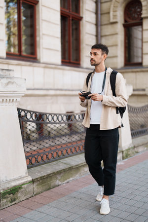 Young man exploring city streets with camera and backpackの写真素材