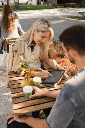 Young professionals collaborating at an outdoor cafe with tabletの写真素材