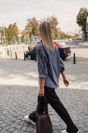 Young woman walking on urban street with stylish handbagの写真素材