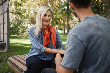 Happy couple enjoying a conversation in a sunny parkの写真素材