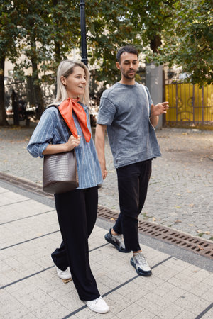 Casual friends enjoying a sunny walk through the city parkの写真素材
