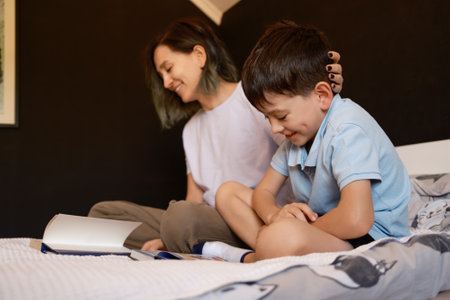 Mother and son sharing a joyful moment while reading a book togetherの写真素材