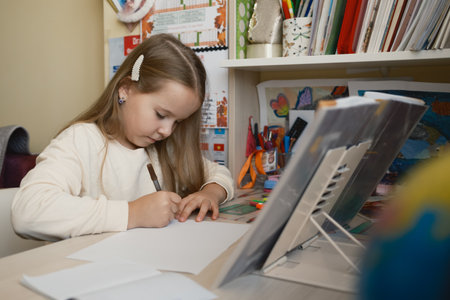 Young girl focused on doing homework at her organized desk in her room