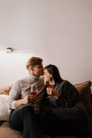 Romantic couple sharing a moment with red wine in a cozy settingの写真素材