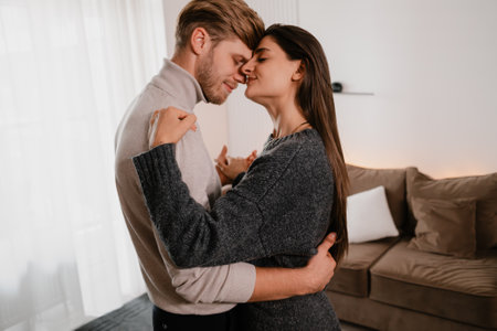 Young couple embracing intimately in a cozy apartment living spaceの写真素材