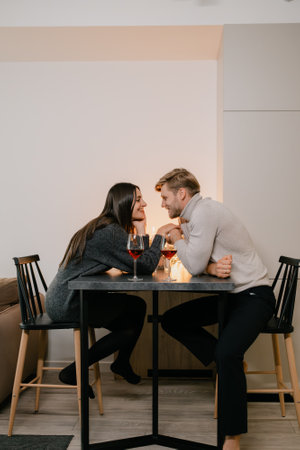 Couple enjoying a romantic dinner with wine and candles indoorsの写真素材
