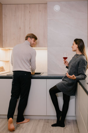 Couple Enjoying a Conversation While Preparing a Meal in a Modern Kitchenの写真素材