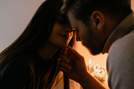 Couple sharing a romantic and intimate moment by candlelight in warm ambianceの写真素材